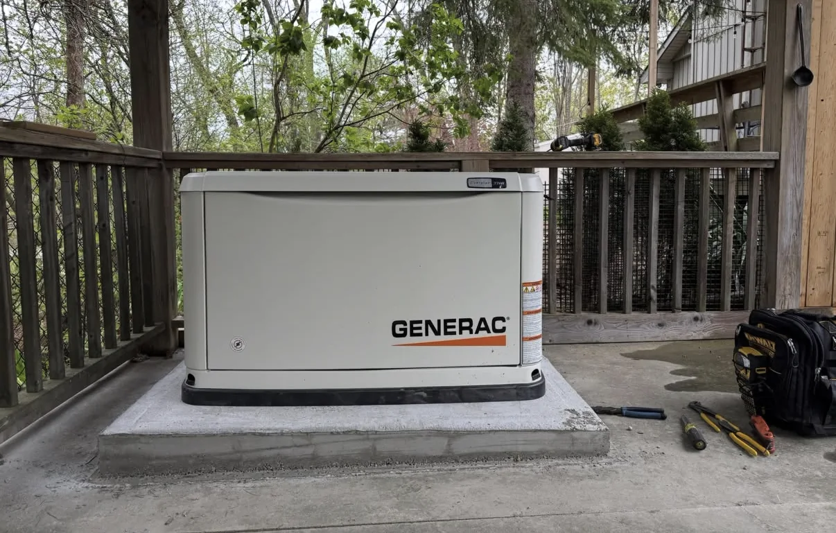 Installed Generac standby generator on a concrete base beside a residential deck.