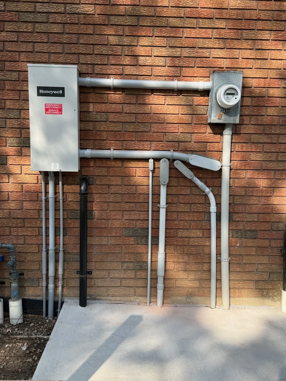 200 amp transfer switch mounted on brick wall with electrical conduits and meter