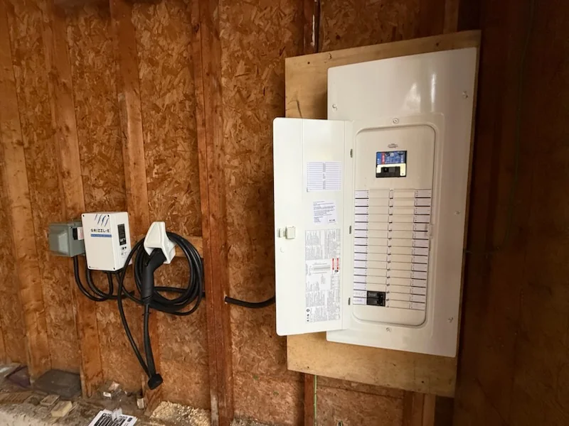 Electric vehicle charger mounted on wooden wall near electrical panel