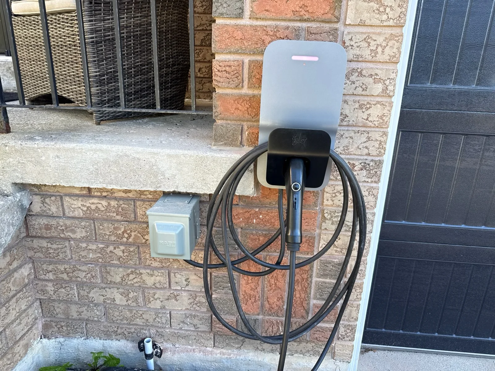 Residential electric vehicle charger installed on brick exterior wall