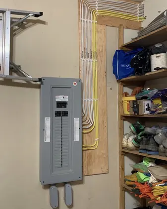 New grey main electrical panel with neatly routed cables beside storage shelves.