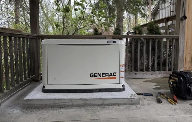 Installed Generac standby generator on a concrete base beside a residential deck.