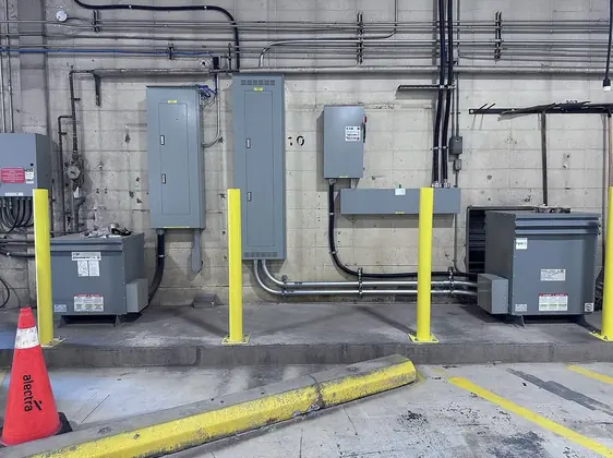 Electrical panels, transformers and conduit installed along a block wall at Alectra Utilities.