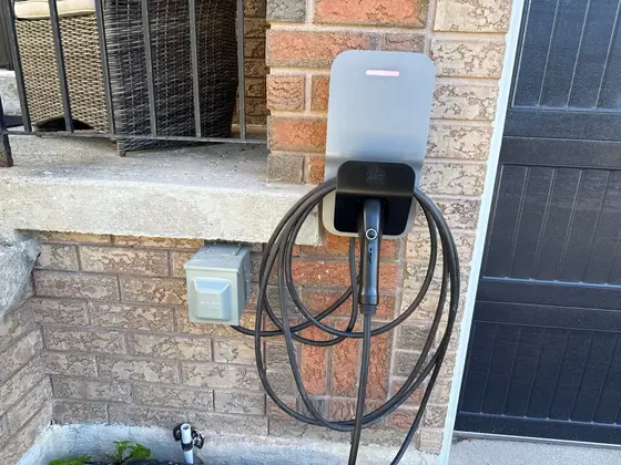 Residential electric vehicle charger installed on brick exterior wall